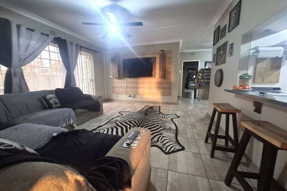 Open-plan living area featuring tiled flooring, a built-in media wall, and a breakfast bar connecting to the kitchen space.