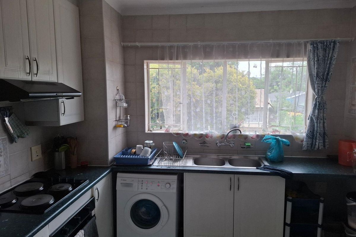 Functional kitchen featuring built-in cabinetry, electric hob, oven, extractor fan, and a double sink with a window view.
