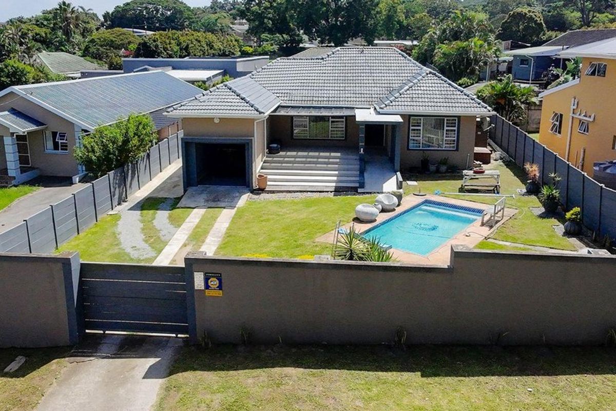 Aerial view of a residential property featuring a tiled roof house, private swimming pool, paved driveway, and secure perimeter walling.