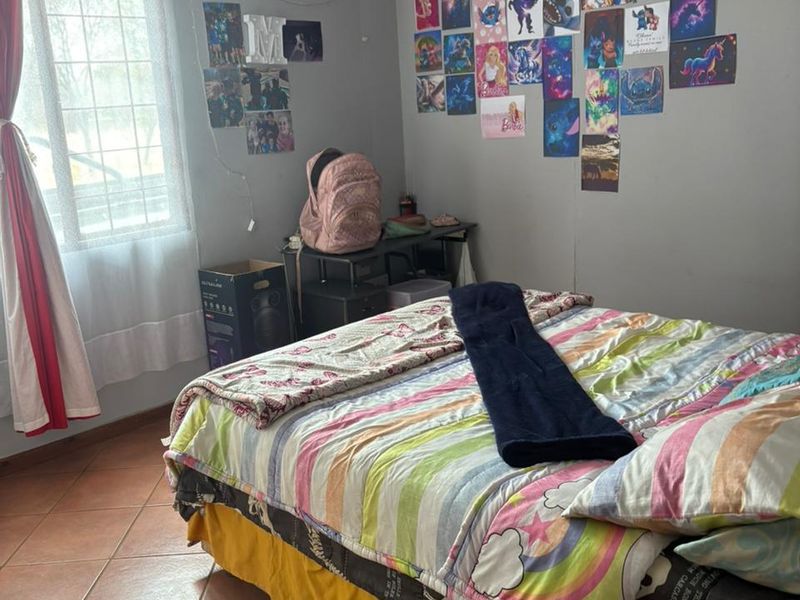 A functional bedroom featuring tiled flooring and a window, providing a neutral base for personalization.