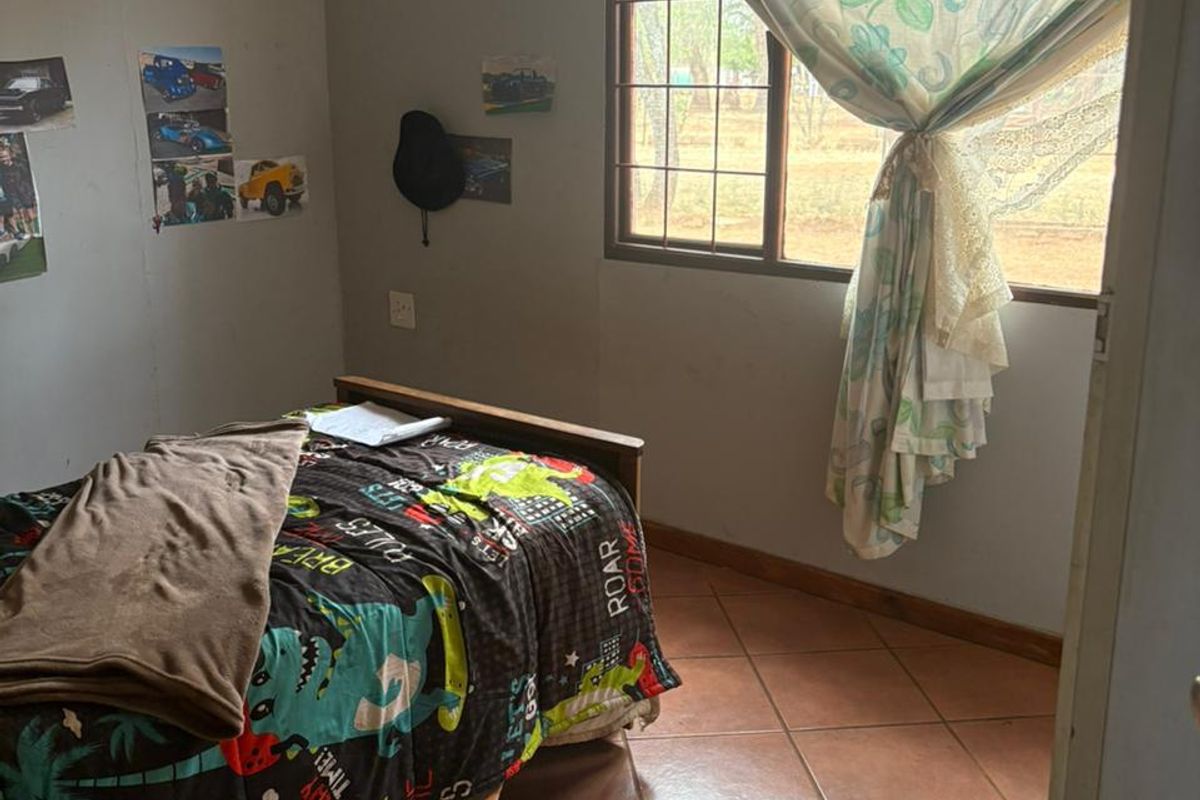 A bedroom featuring tiled flooring and a window with security bars, requiring cosmetic updates to improve its overall appeal.