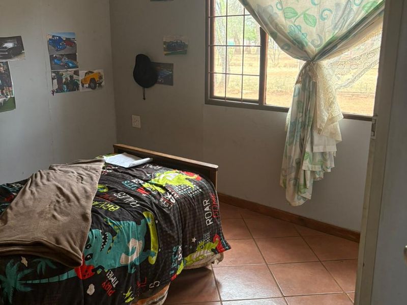 A bedroom featuring tiled flooring and a window with security bars, requiring cosmetic updates to improve its overall appeal.