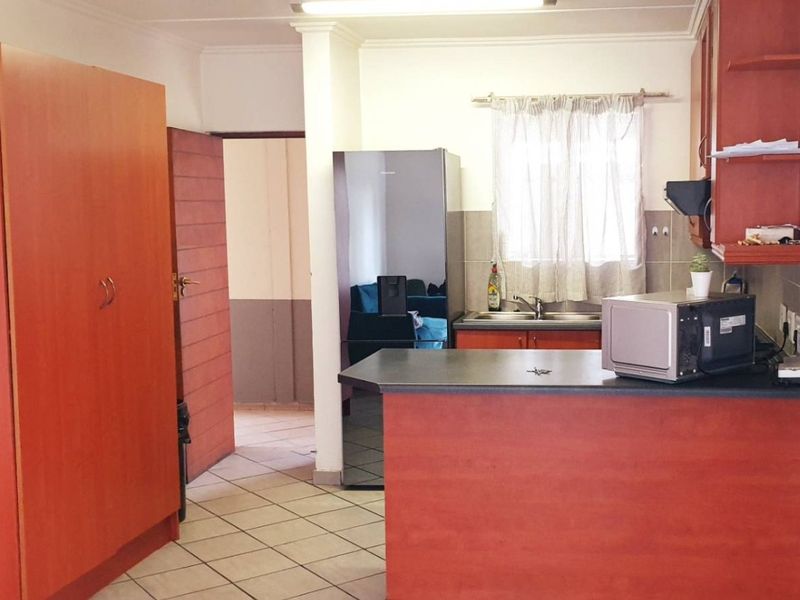 A functional kitchen featuring wood-finish cabinetry, laminate countertops, a breakfast bar, and tiled flooring, providing a practical layout for daily meal preparation.