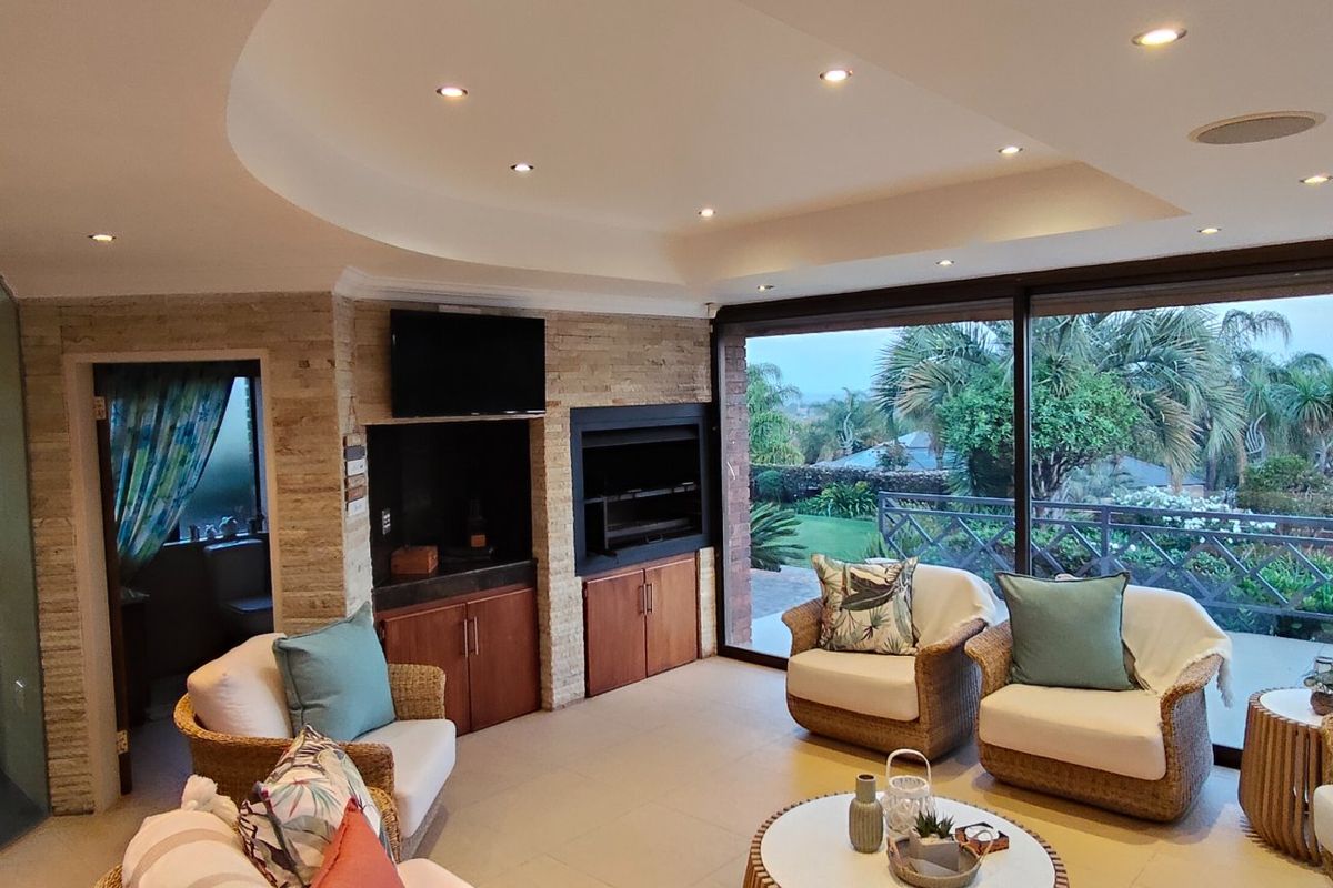 Spacious living area featuring a stone feature wall, built-in fireplace, recessed ceiling lighting, and large sliding glass doors opening to an outdoor view.