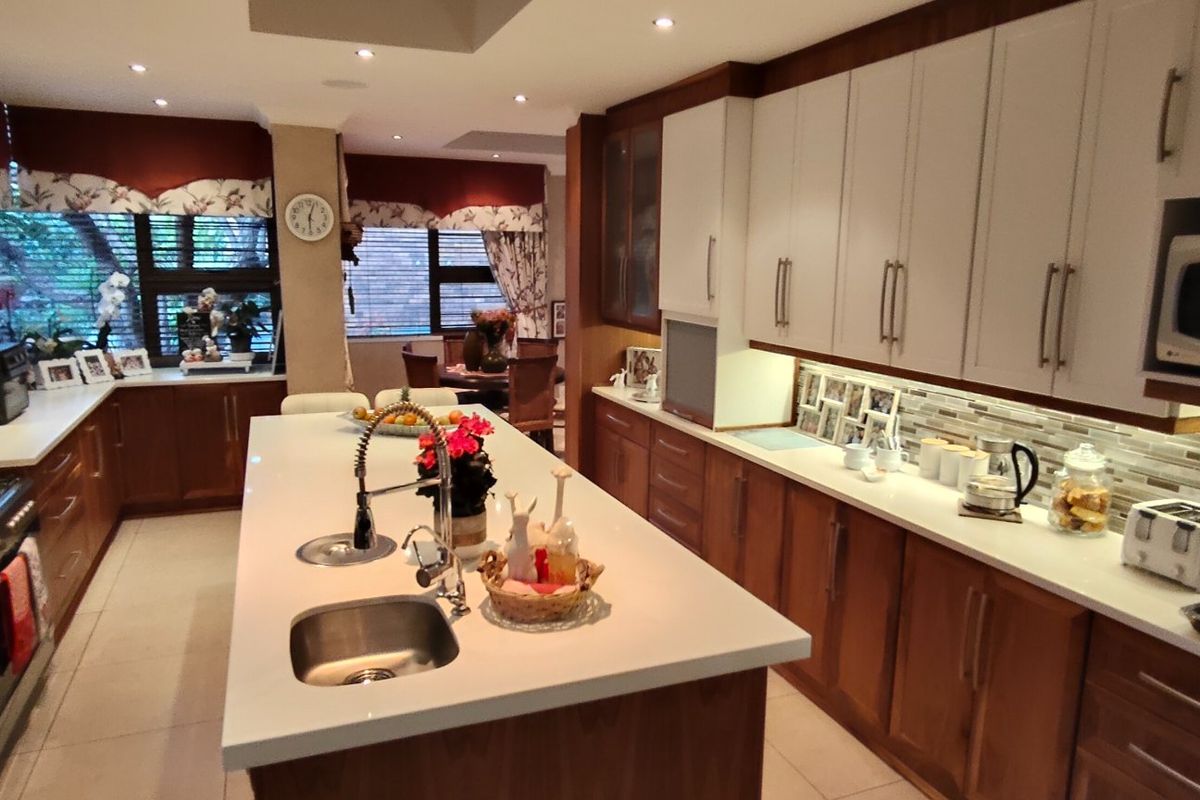 Spacious modern kitchen featuring a large central island, stone countertops, built-in appliances, and ample cabinetry with integrated lighting.
