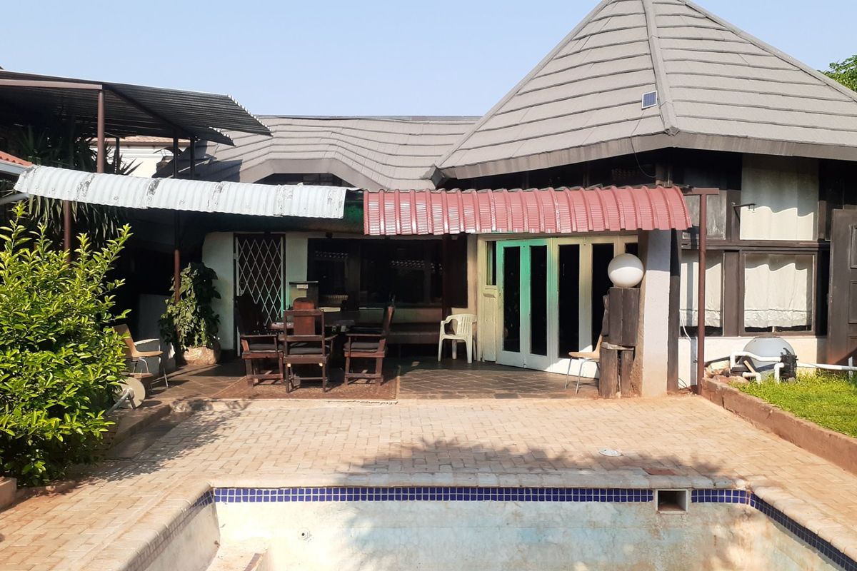 Rear view of the property featuring a paved patio area, covered outdoor space, and an in-ground swimming pool.