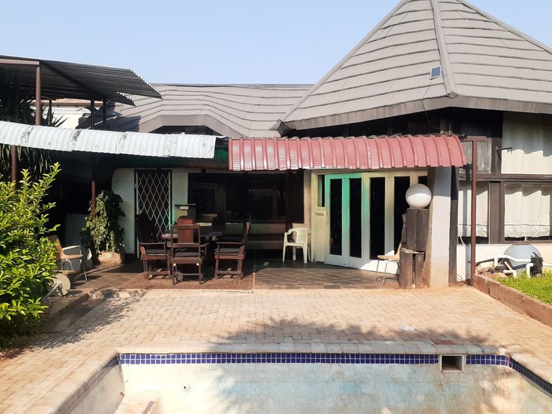 Rear view of the property featuring a paved patio area, covered outdoor space, and an in-ground swimming pool.