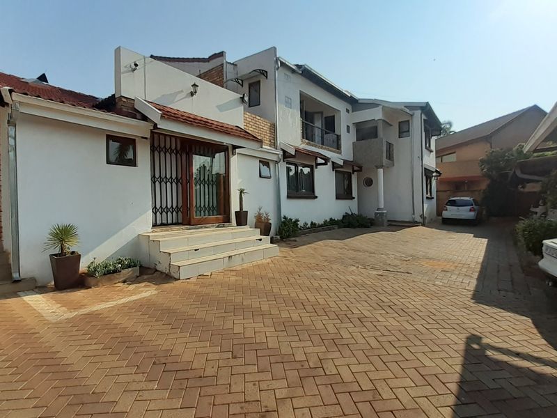 Front exterior view of the property featuring a paved driveway, entrance steps with security gate, and a multi-level facade with balcony.