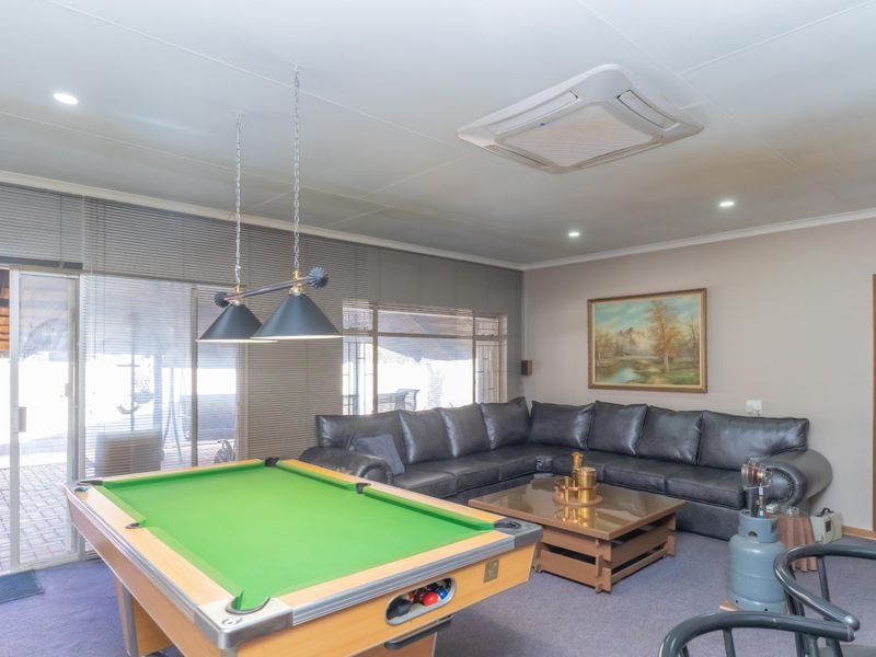 Spacious living area featuring a recessed ceiling air conditioning unit, large sliding glass doors with venetian blinds, and integrated downlighting.