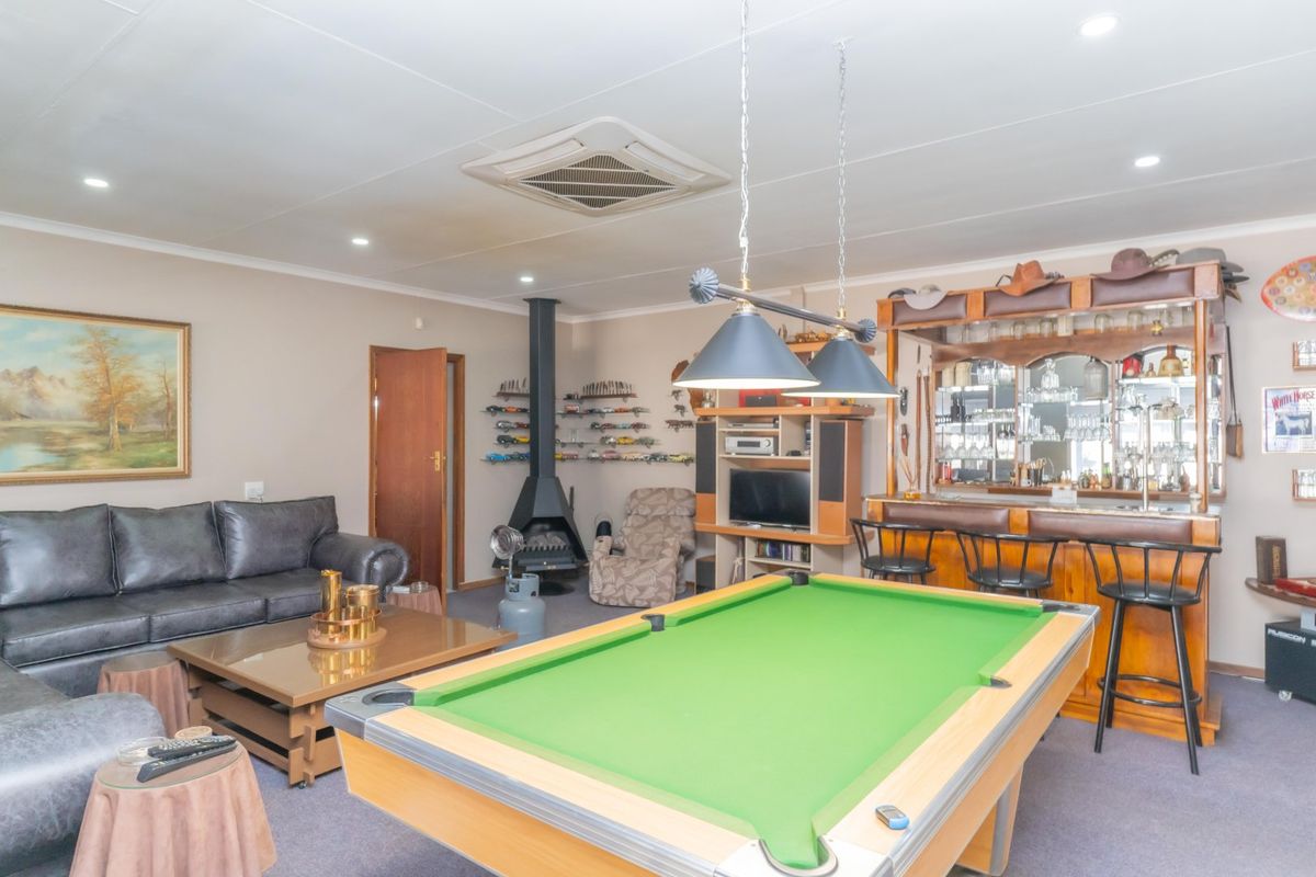 Spacious living area featuring a built-in bar, a freestanding fireplace, and recessed ceiling lighting, offering a versatile space for entertainment and relaxation.