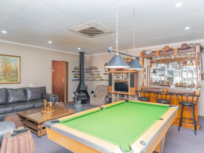 Spacious living area featuring a built-in bar, a freestanding fireplace, and recessed ceiling lighting, offering a versatile space for entertainment and relaxation.