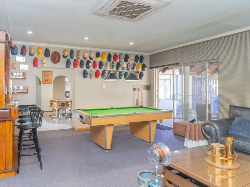 Spacious entertainment room featuring a built-in bar, pool table area, and direct access to the outdoor patio through sliding glass doors.