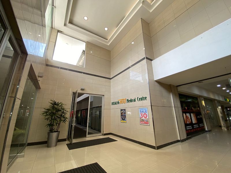 Spacious commercial entrance lobby featuring high ceilings, ceramic wall tiles, and polished floor tiles, providing a professional and bright reception area.