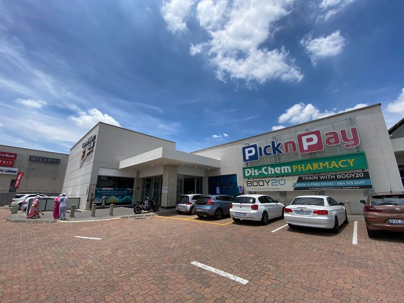Front exterior view of a commercial shopping center featuring paved parking, prominent retail signage, and a covered entrance canopy.
