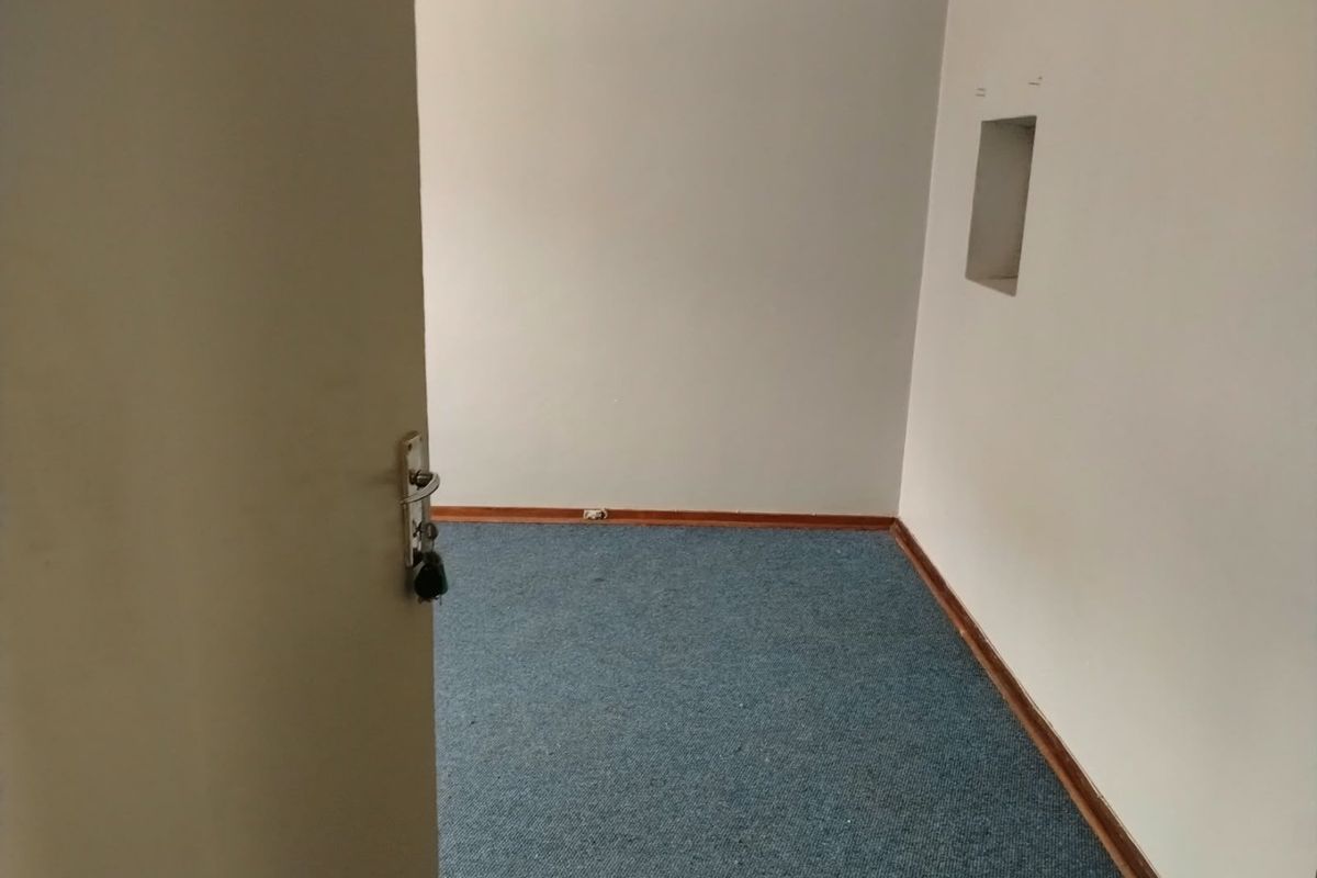 An empty bedroom featuring blue carpet flooring, neutral walls, and a small built-in wall niche.