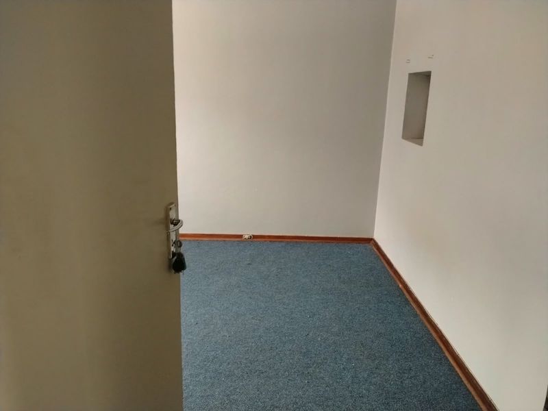 An empty bedroom featuring blue carpet flooring, neutral walls, and a small built-in wall niche.