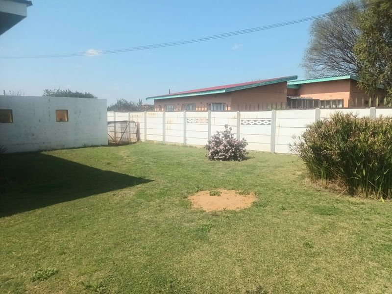 A private backyard area featuring a lawn and enclosed by a precast concrete boundary wall.