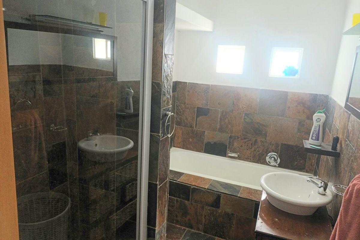 A bathroom featuring a built-in bathtub, a separate shower enclosure, and vessel sinks with natural slate tile finishes.