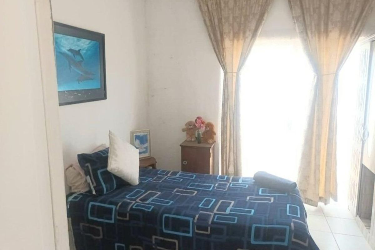 A compact bedroom featuring tiled flooring and a built-in wardrobe, requiring cosmetic updates to the wall finishes to improve the overall aesthetic.