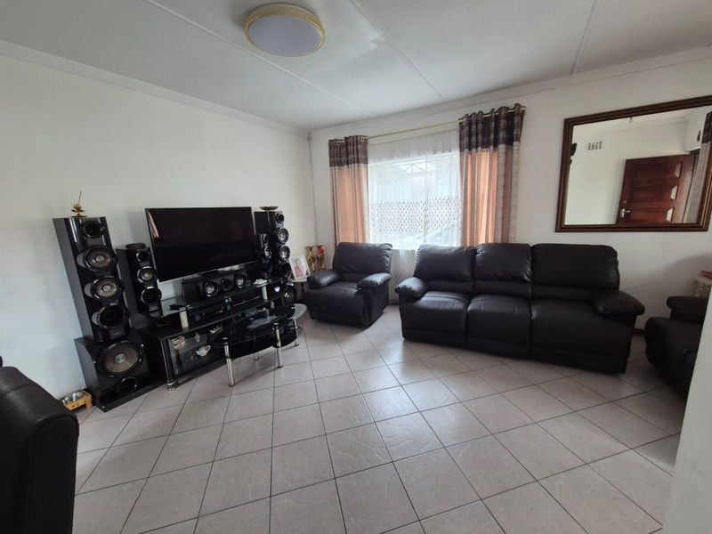 A functional living room featuring neutral tiled flooring and a central ceiling light fixture, providing a comfortable and well-maintained space for relaxation.