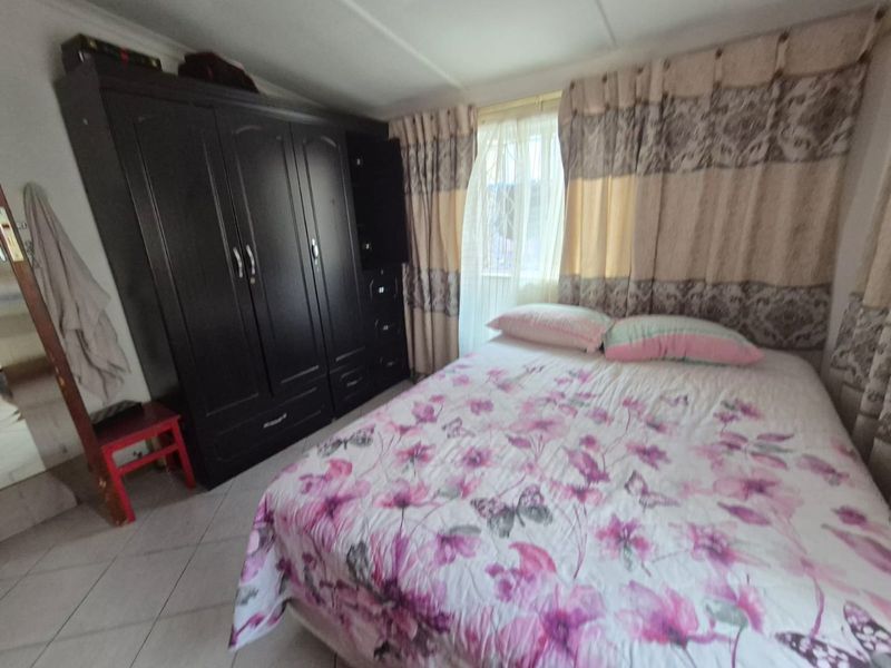 A functional bedroom featuring tiled flooring and a large built-in wardrobe, providing essential storage space.