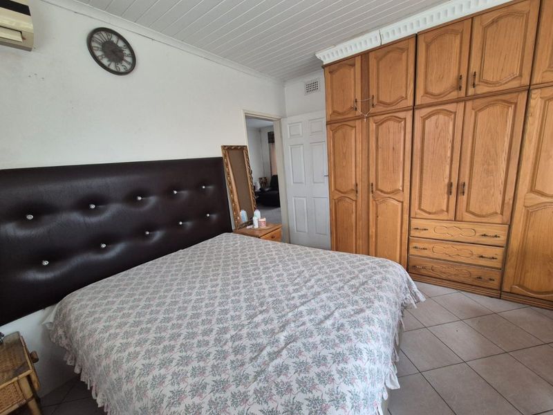 A bedroom featuring built-in wooden wardrobes, tiled flooring, and a tongue and groove ceiling, offering a functional space with potential for modern updates.