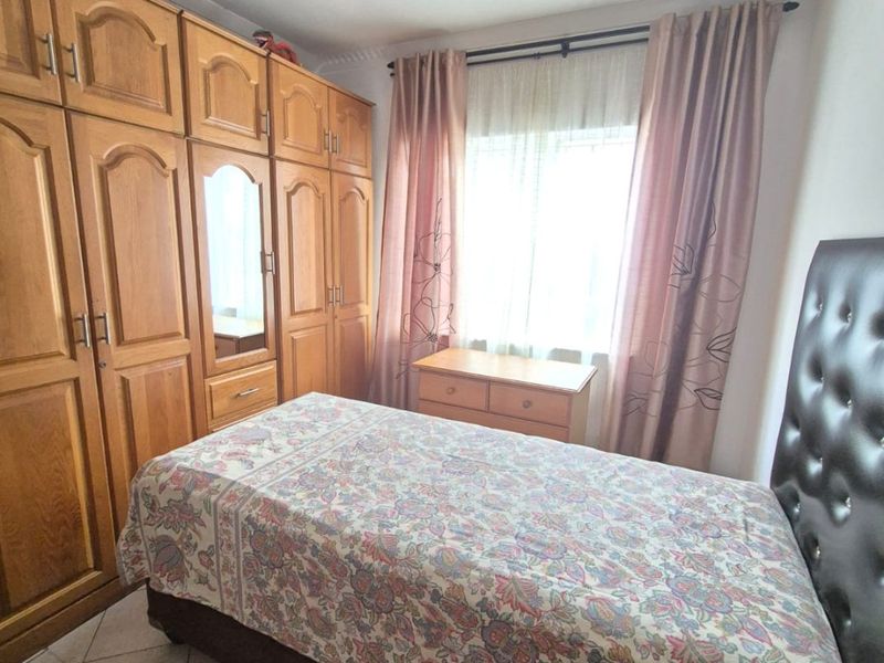 A bedroom featuring built-in wooden wardrobes and tiled flooring, offering functional storage space and natural light.