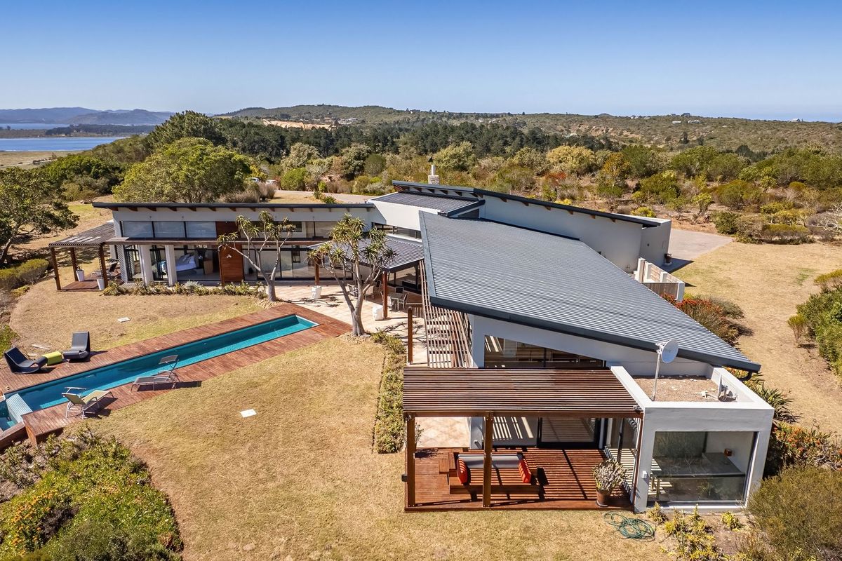 Aerial view of a modern farm property featuring a swimming pool, timber decking, pergolas, and expansive rural landscape views.