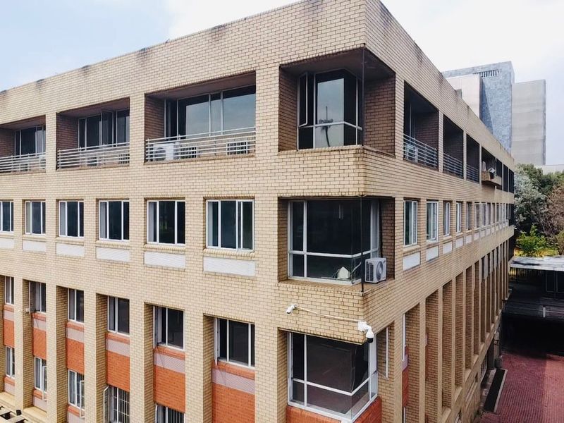 An elevated view of a multi-story commercial building featuring a brick facade, aluminum windows, and integrated security and climate control infrastructure.