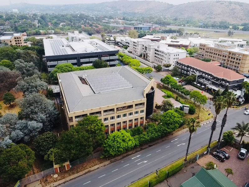 Aerial view of a commercial office complex featuring multiple buildings, landscaped surroundings, and convenient access to main roads.