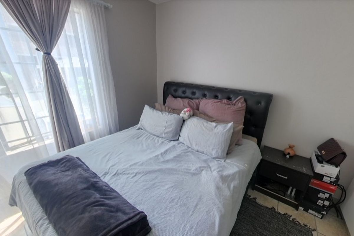 A functional bedroom featuring tiled flooring and natural light through a window with installed curtain tracks.