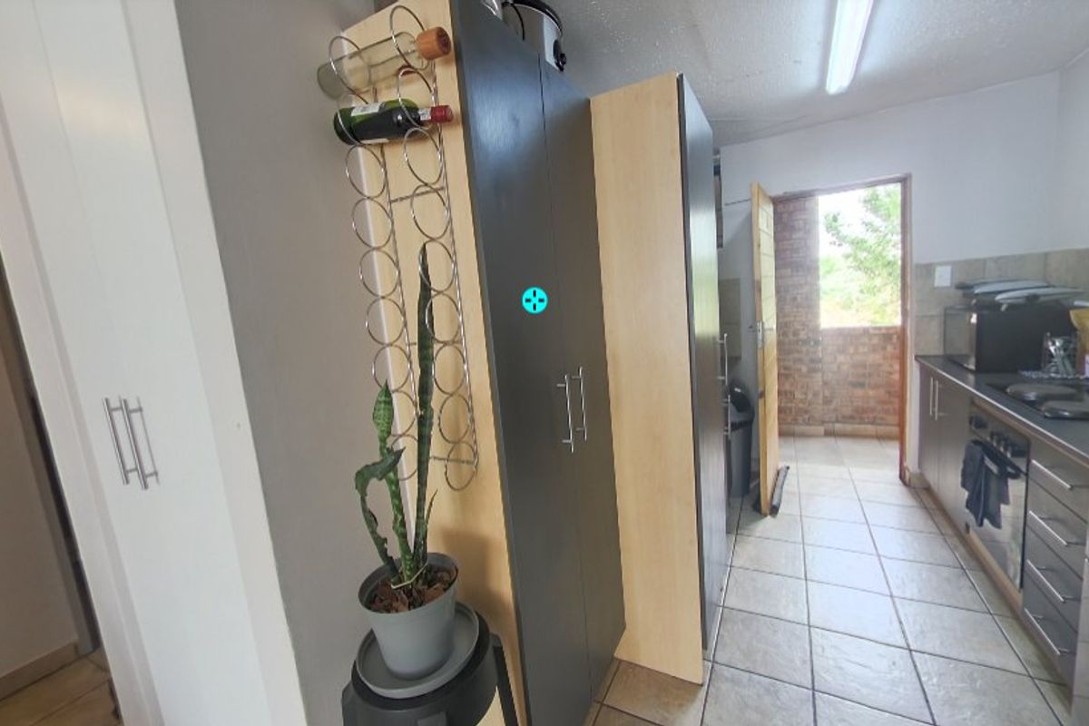 A functional kitchen featuring built-in cabinetry, tiled flooring, and integrated appliances, with direct access to an outdoor balcony area.