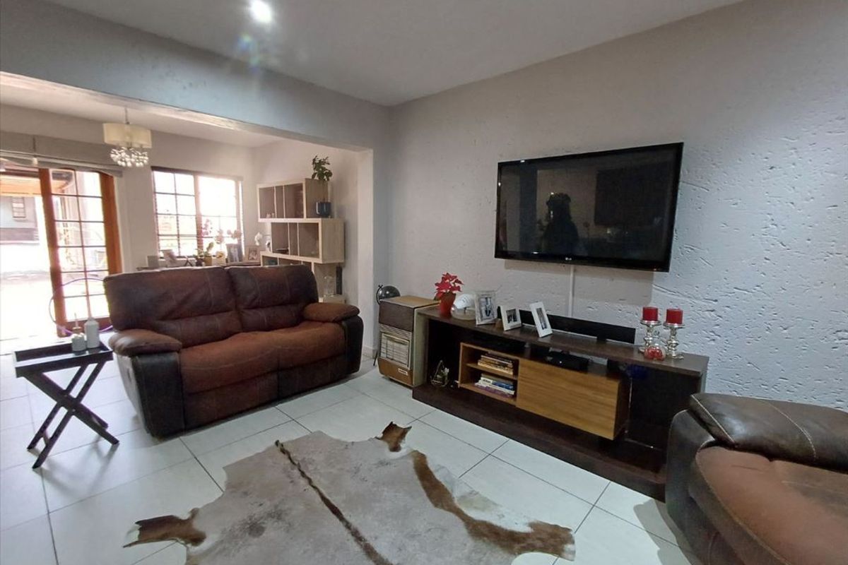 A living room featuring tiled flooring, recessed lighting, and a sliding glass door leading to an outdoor area.