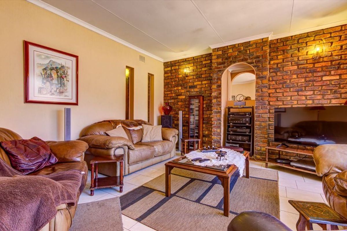 A cozy living room featuring an exposed brick accent wall, arched architectural detail, and neutral tiled flooring.