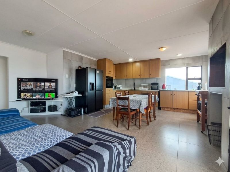 Open-plan living and kitchen area featuring tiled flooring, wooden cabinetry, and a functional layout suitable for modern family living.