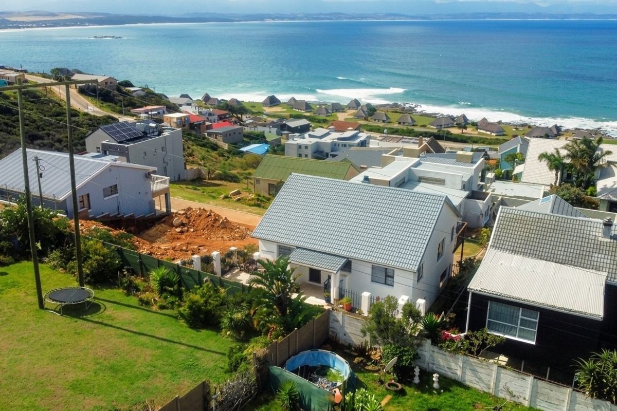 Aerial view of the coastal residential property showcasing the roof structure, surrounding neighborhood, and proximity to the ocean.