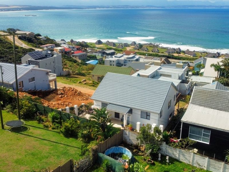 Aerial view of the coastal residential property showcasing the roof structure, surrounding neighborhood, and proximity to the ocean.