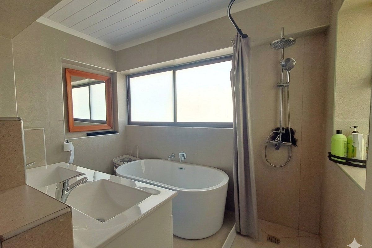Modern bathroom featuring a freestanding bathtub, a separate shower area, and a double vanity with tiled finishes throughout.