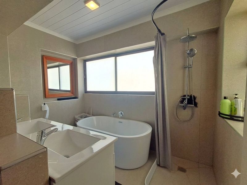 Modern bathroom featuring a freestanding bathtub, a separate shower area, and a double vanity with tiled finishes throughout.