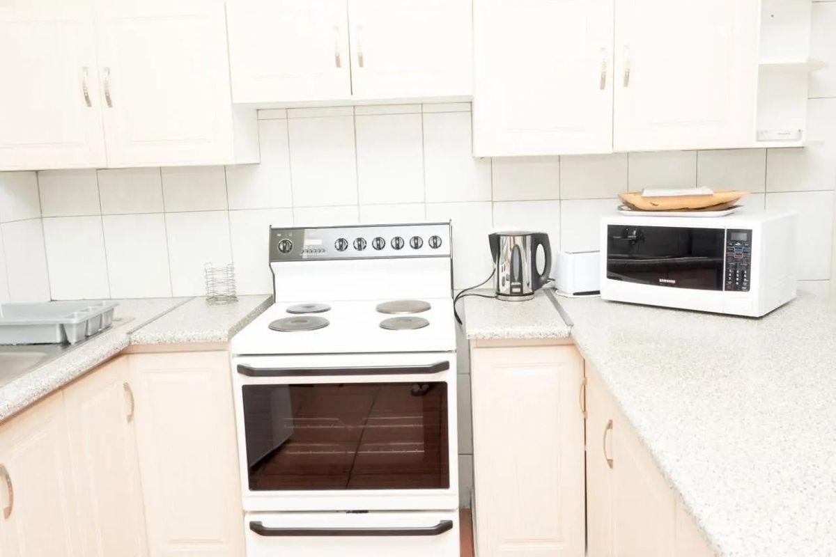 A functional kitchen featuring white cabinetry, laminate countertops, a tiled backsplash, and a freestanding electric stove.