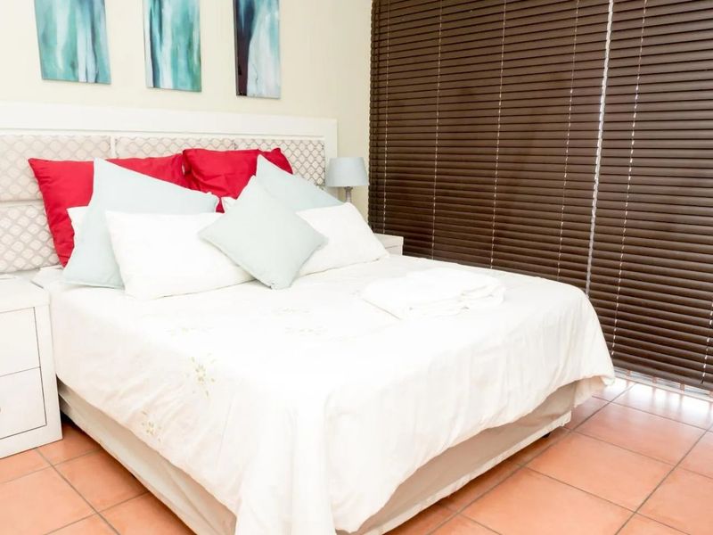 A bedroom featuring tiled flooring and dark venetian blinds, providing a functional space with neutral wall finishes.