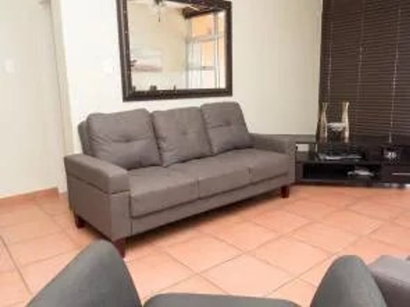 A living room area featuring tiled flooring and dark venetian blinds, providing a functional space for relaxation.