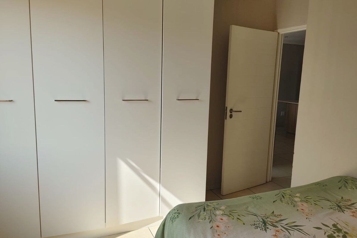 A bedroom featuring white built-in cupboards and tiled flooring, with an internal door leading to an adjacent space.