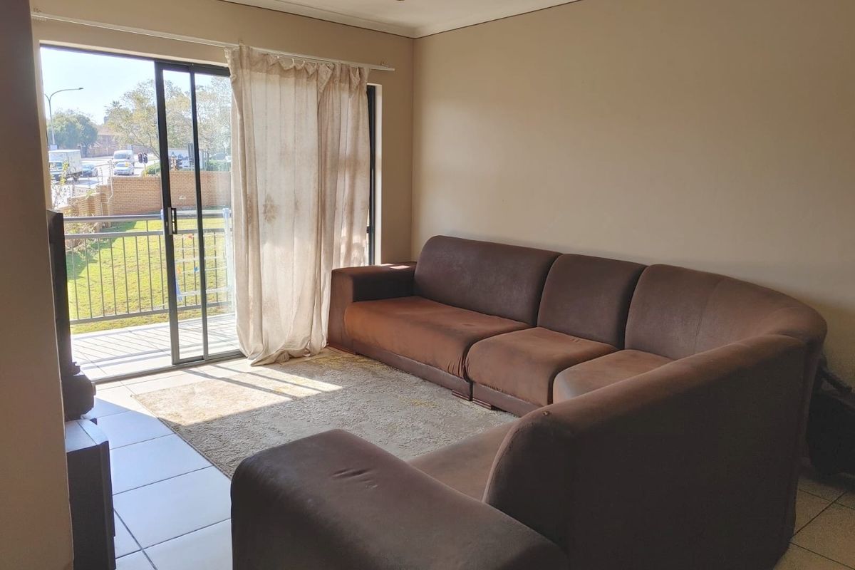 A living room featuring tiled flooring and a large sliding glass door providing access to a balcony with natural light.