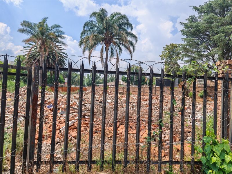 Vacant residential land featuring a metal security fence and significant demolition rubble on site, ready for clearing and new development.