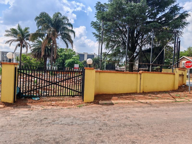 Vacant residential land featuring a perimeter wall, metal gate, and a large billboard structure, currently containing demolition debris.