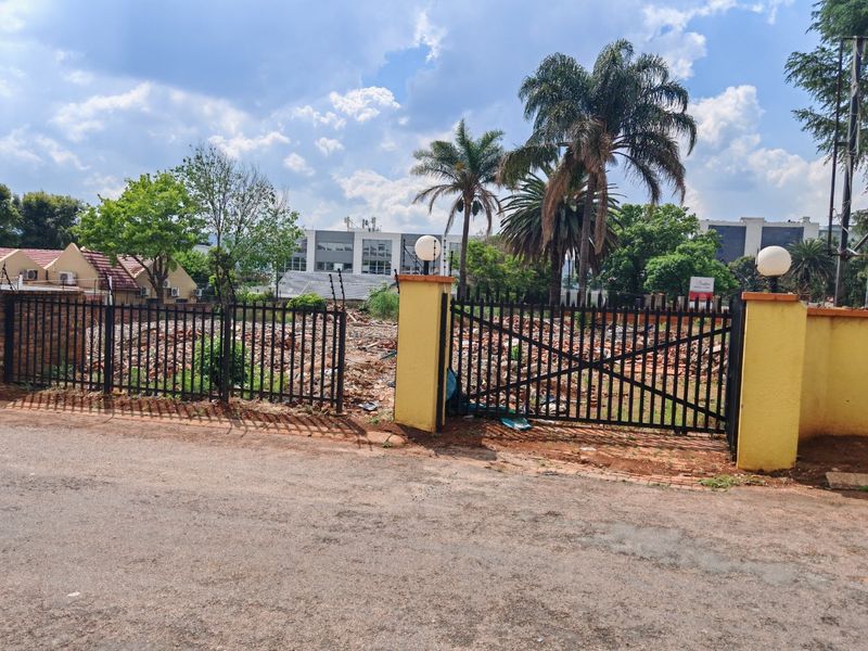 Vacant residential land featuring perimeter metal fencing, gated entrance, and electric security fencing, currently containing demolition debris from previous structures.
