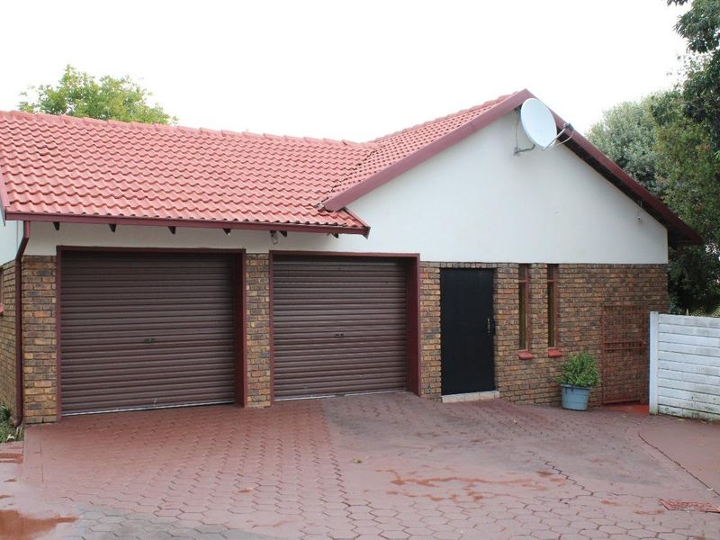 A detached double garage featuring a tiled roof, brick exterior, and a paved driveway.