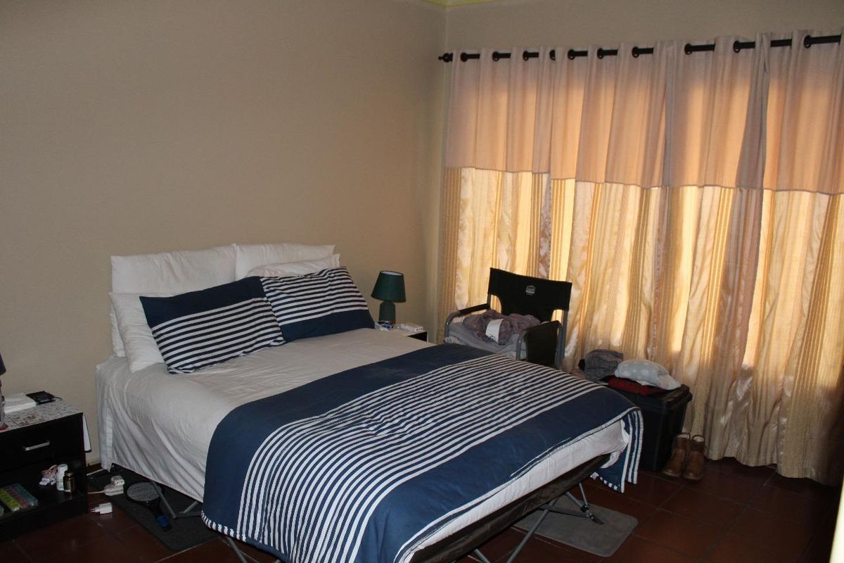 A standard bedroom featuring tiled flooring and large window curtains, offering a functional space ready for personalization.