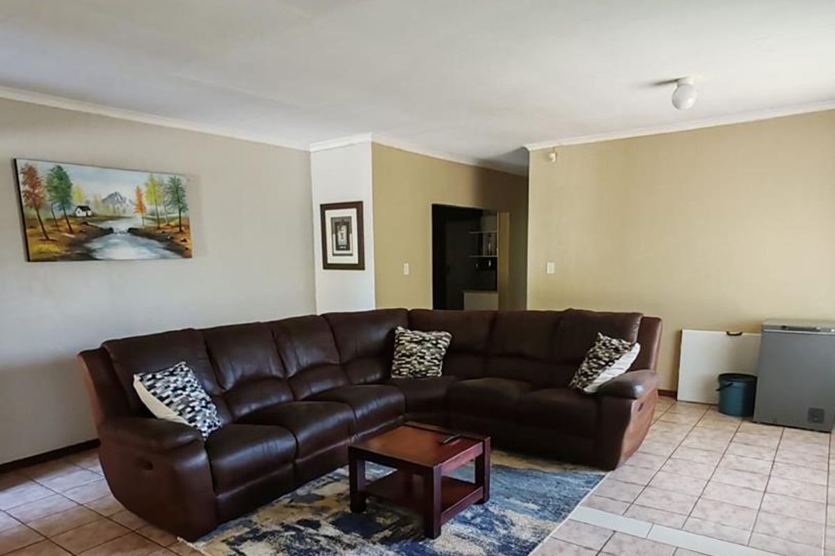 Spacious living area featuring neutral wall tones, ceramic tiled flooring, and simple ceiling lighting, offering a functional layout for comfortable family living.